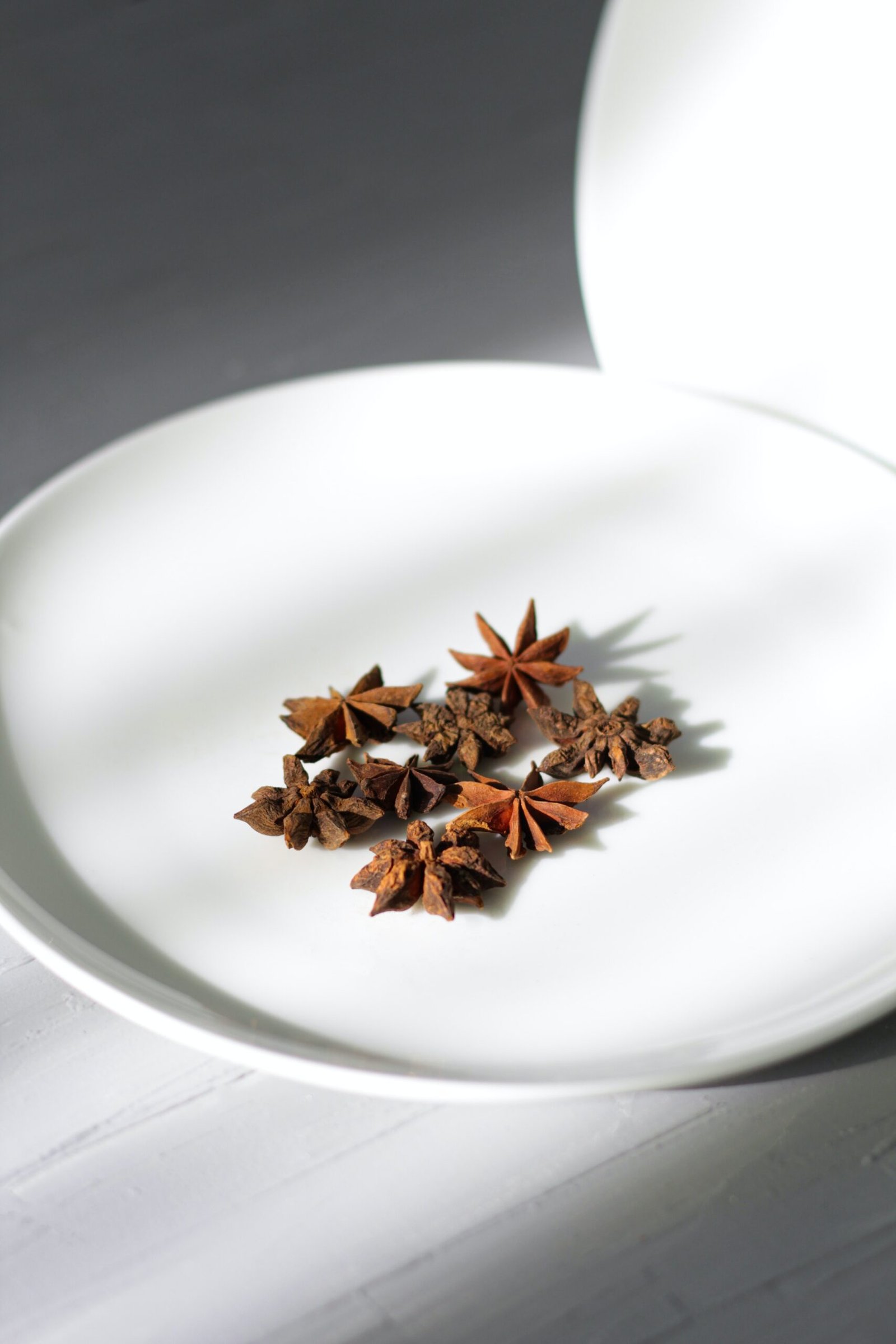 a white plate topped with star anise on top of a table